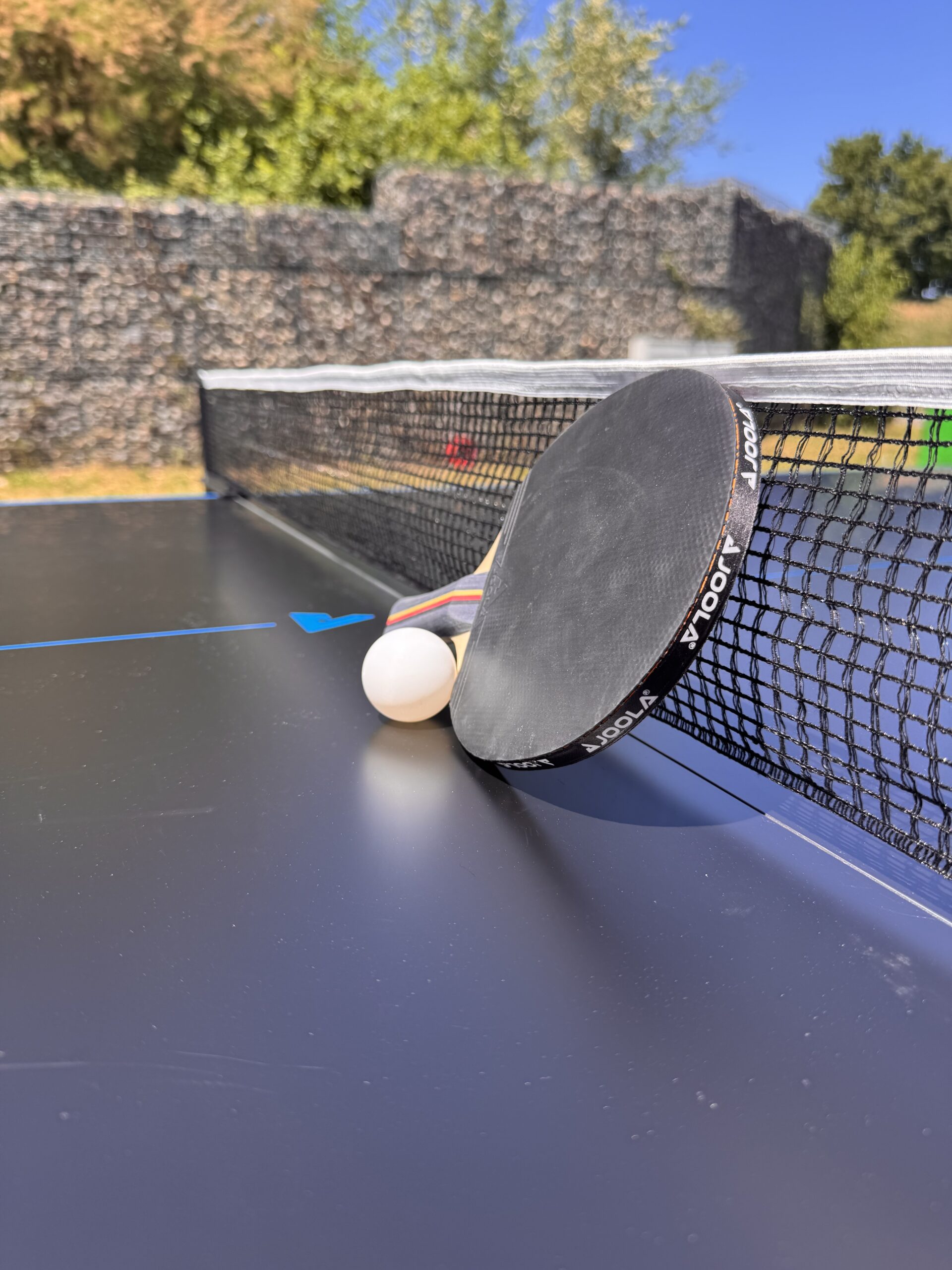 Tischtennisschläger und Ball auf einer professionellen Tischtennisplatte im Freien